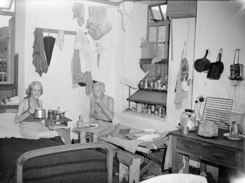 Two internees in a crowded room at Stanley camp, Hong Kong, 1945.