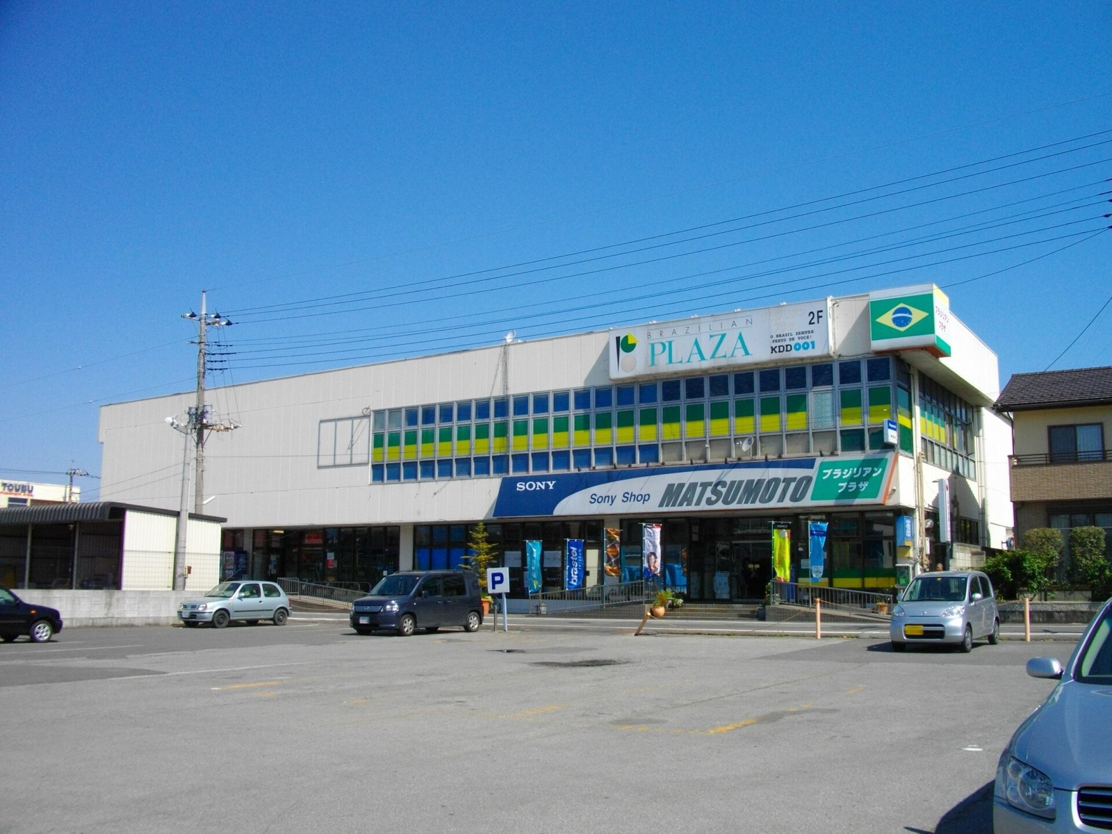 A two-storey shopping centre with a Brazilian flag and Portuguese and Japanese signs in Oizumi, Gunma, 2010.