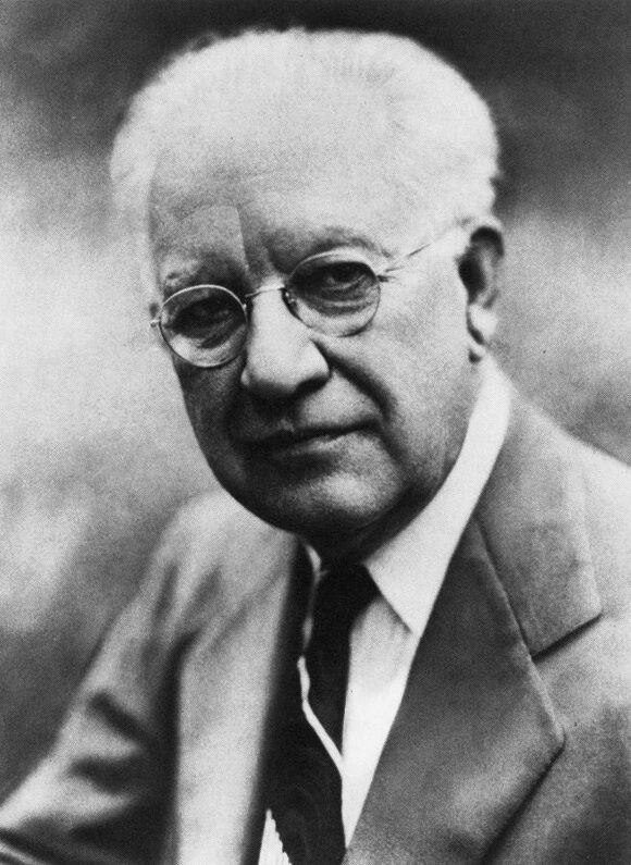 Head-and-shoulders portrait of the sociologist Robert E. Park, an older man with round glasses, suit and tie.