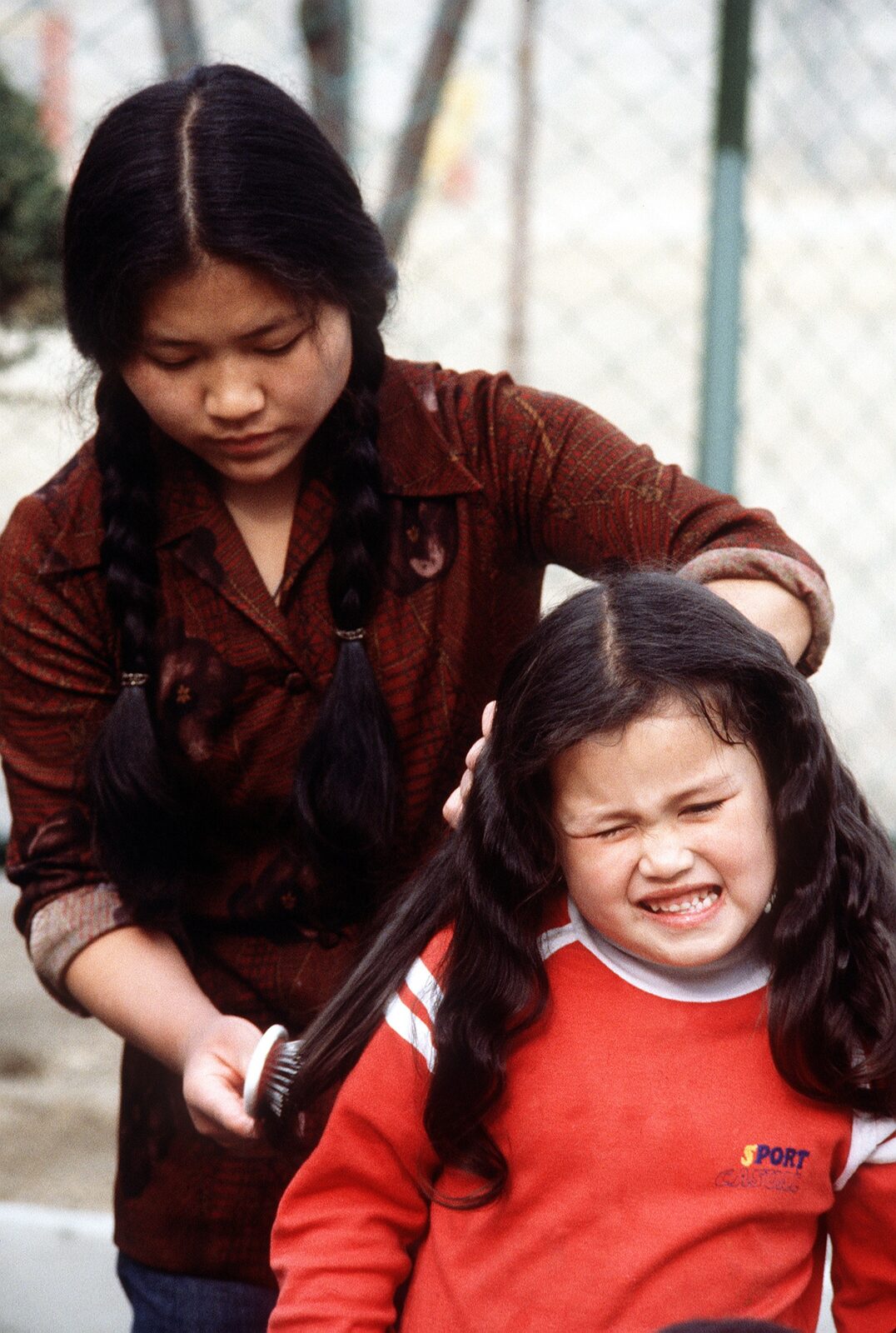 An older girl brushes a younger girl's hair at a home for children of Korean and American parentage in Bupyeong, South Korea, 1980.